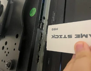 Game stick being plugged into the HDMI port of a TV