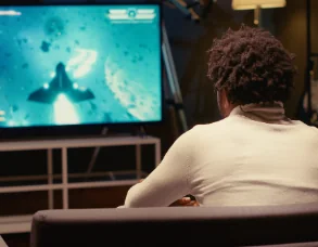 Person playing a retro space shooter on a large TV