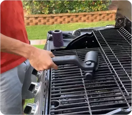 Die GrillSync Bürste im Einsatz auf einem verschmutzten Grillrost